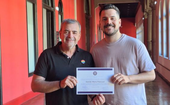 Vicerrector y ganador del premio posan de pie con el diploma en la mano