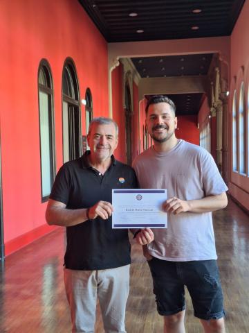 Entrega premio TFG 2025 Vicerrector y ganador del premio posan de pie con el diploma en la mano